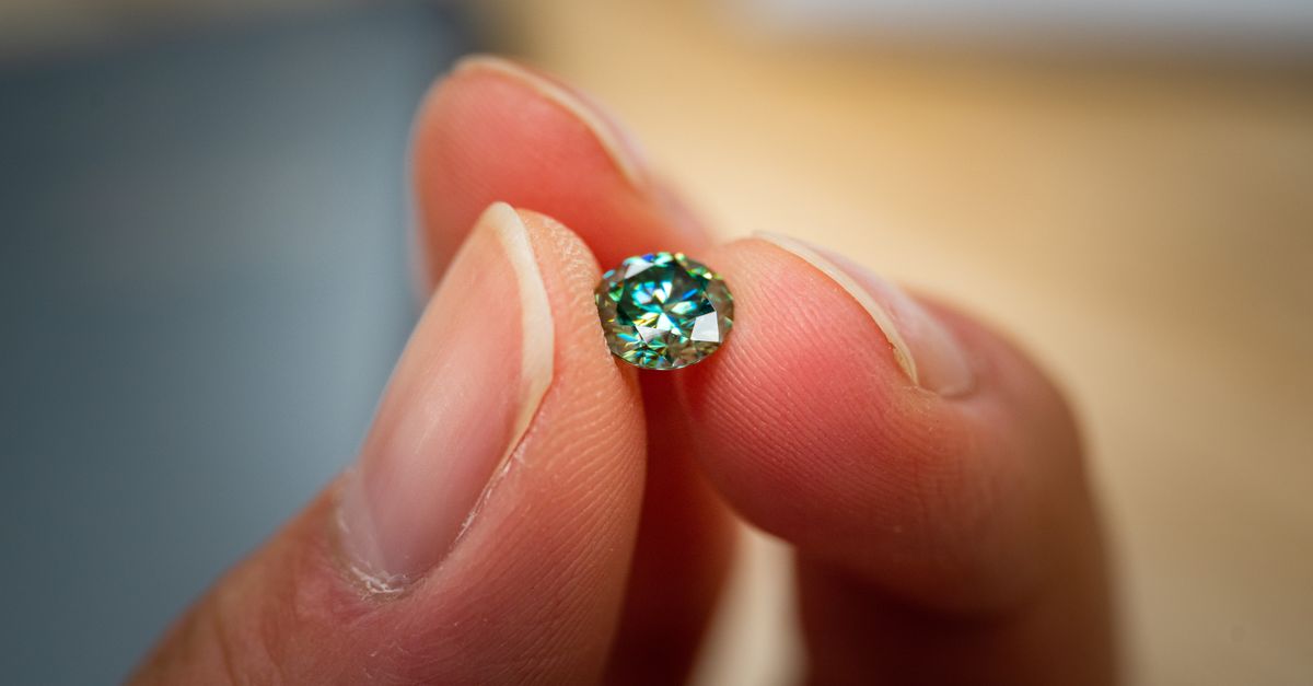 A detailed macro shot of a green diamond held between fingertips, showcasing clarity and brilliance.